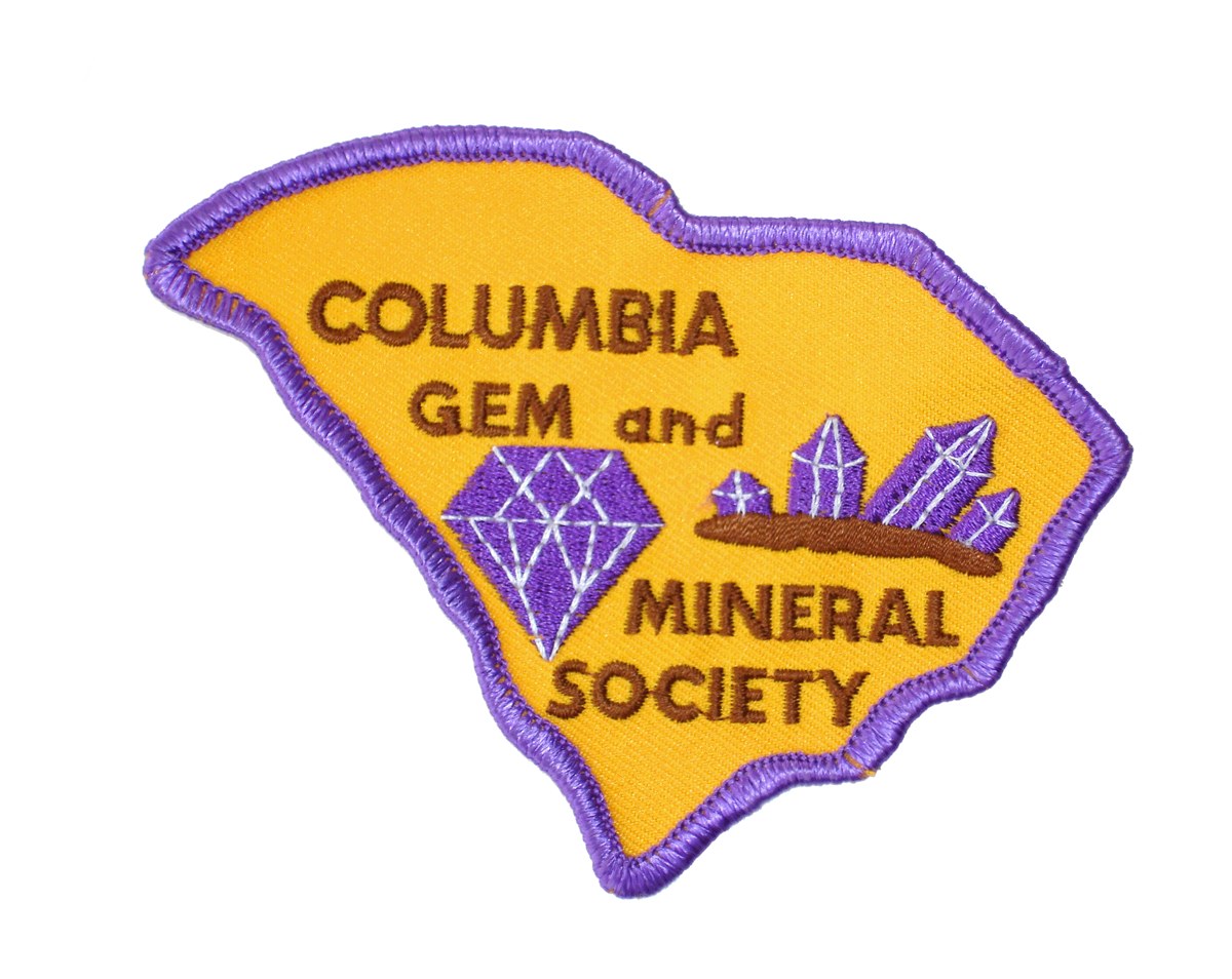 Columbia Gem and Mineral Society embroidered club patch in the shape of South Carolina, with the club name, a purple diamond and a cluster of amethyst crystals on a gold field, from the official CGMS website.