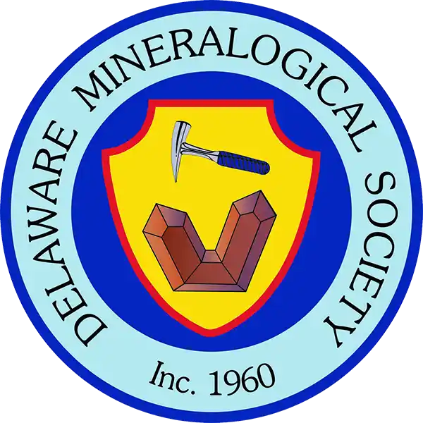 Delaware Mineralogical Society round seal with a rock hammer and a twinned crystal on a yellow shield and the words Inc. 1960, from the official DMS website.