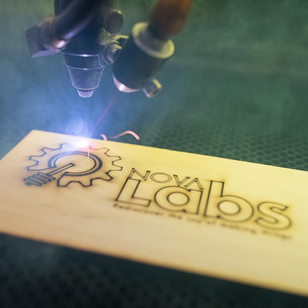 Laser engraving the Nova Labs logo onto wood, the official og:image from the Nova Labs makerspace website.